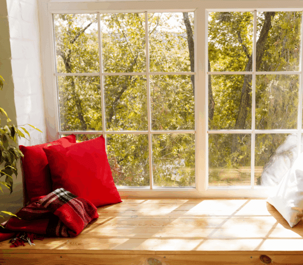 Cozy window seat with red pillows.