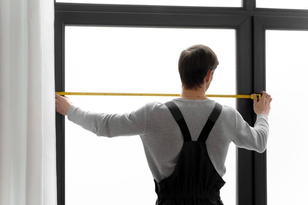 man measuring window before replacing