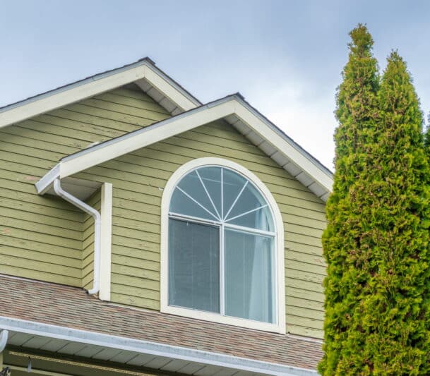 White arched palladian window installed on the upper gable of a green-sided home in Terrace, Ontario — HTR Windows and Doors