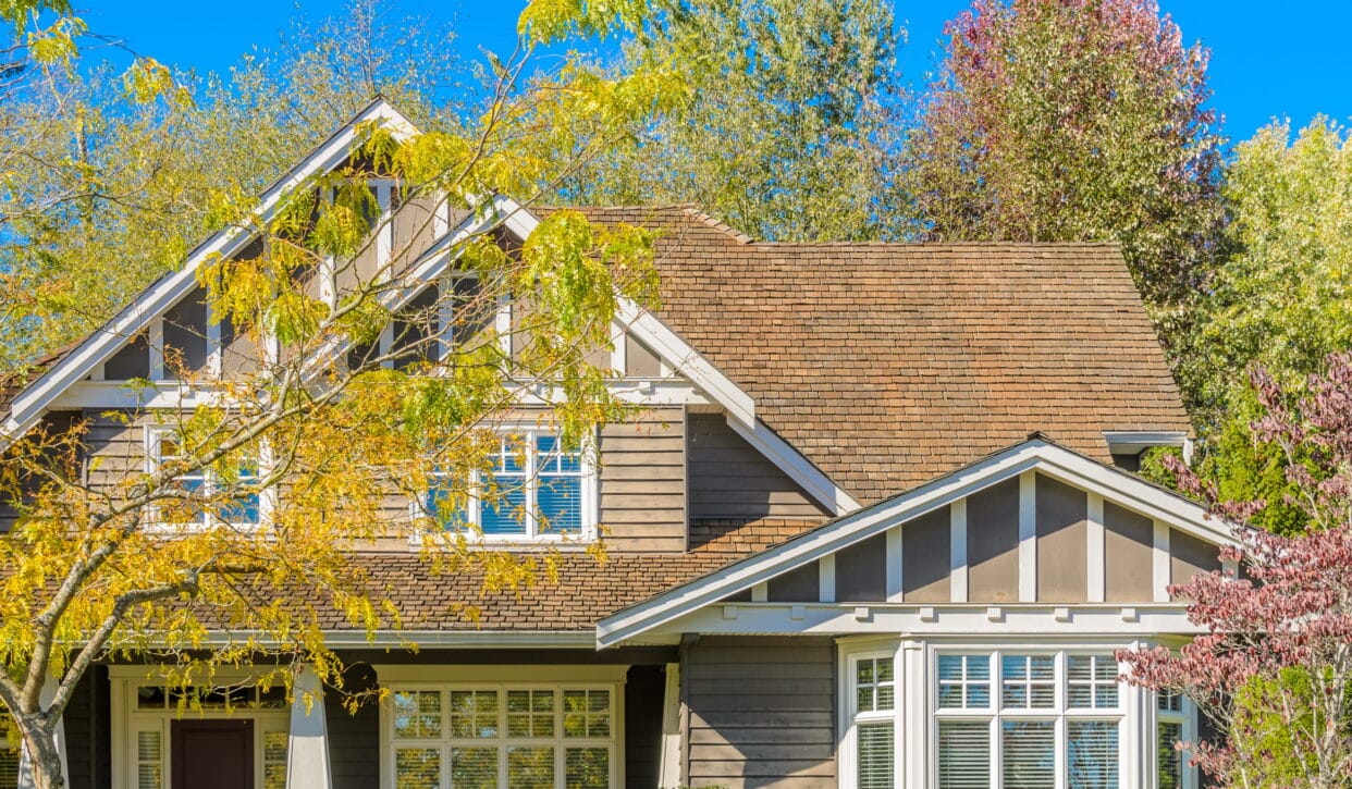 Replaced white multi-pane casement and bay windows on a brown wood-sided craftsman home in Kitimat, BC — HTR Windows and Doors